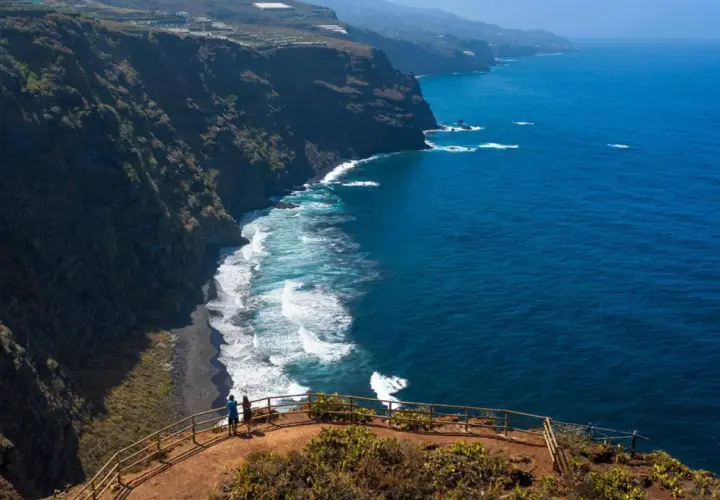 Pareja admira la playa de nogales, una costa volcánica de arena negra bañada por el azul intenso del océano.