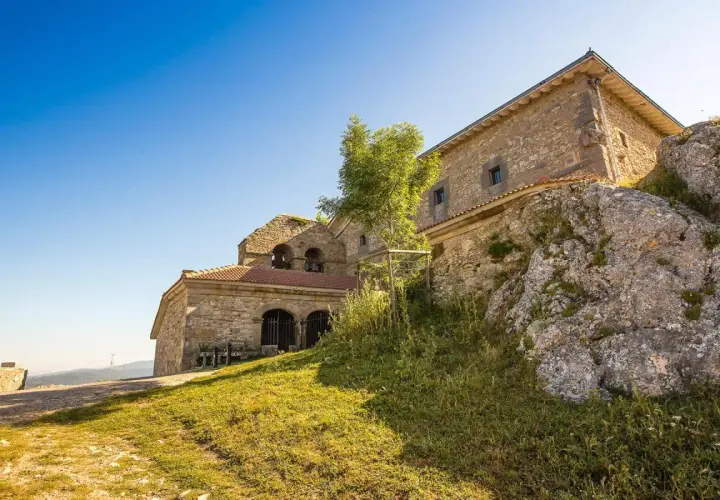Antiguo santuario de oro en la cima de una colina rocosa, con un cielo azul brillante.