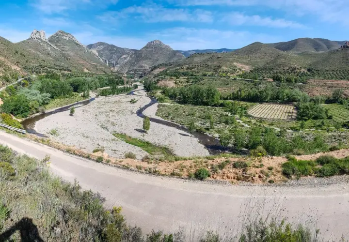 Paisaje montañoso con río y viñedos. La carretera serpentea, guiando hacia Arnedo.