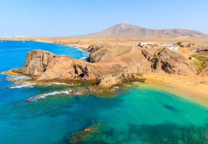 Aguas turquesas y arena dorada en una de las mejores playas de Lanzarote. Un paisaje volcánico se funde con el océano Atlántico.