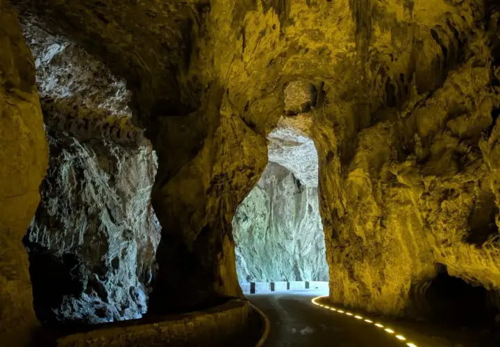 Un camino serpentea a través de las impresionantes cuevas del agua, iluminado por luces doradas que resaltan las formaciones rocosas.