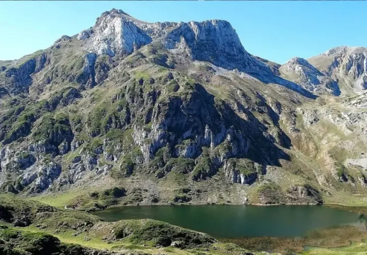 Majestuoso lago en la ruta Lagos de Saliencia, rodeado de imponentes montañas rocosas y vegetación verde.