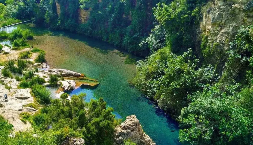 Un río de aguas cristalinas serpentea entre acantilados cubiertos de vegetación exuberante. Los lagos de Anna, un paraíso natural de tonos turquesa y verdes intensos.