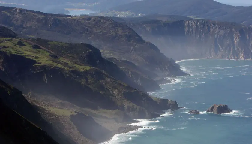 Majestuosos acantilados de San Andrés de Teixido se alzan sobre el mar Cantábrico, con verdes laderas y el azul profundo del océano.