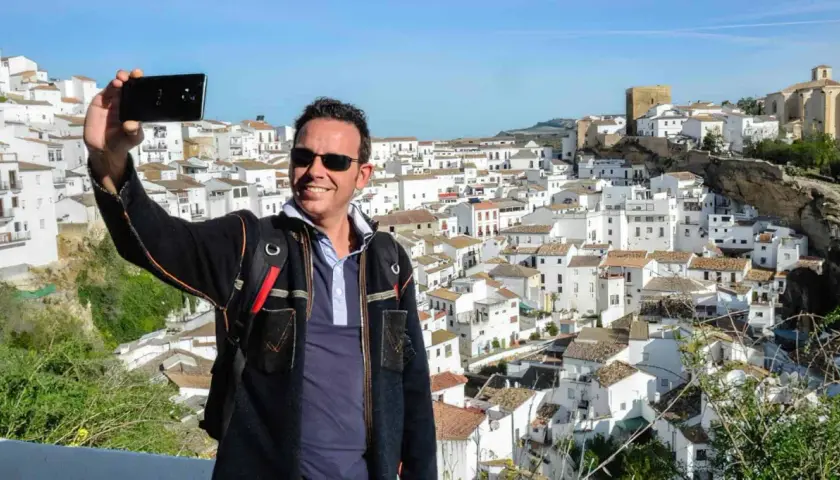 Hombre sonriente se toma selfie con el pueblo blanco de Bornos al fondo. ¡Descubre cómo llegar a este pintoresco lugar!