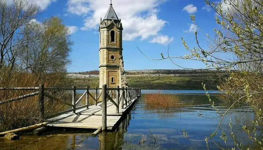 La **catedral de los peces**, una torre solitaria emerge del agua, conectada por un puente de madera.