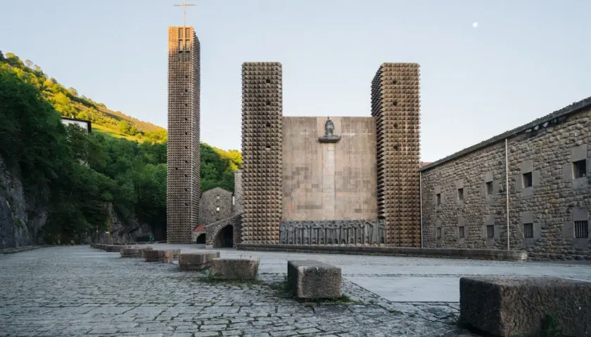 Santuario de Arantzazu con su torre alta, fachada de piedra y esculturas.
