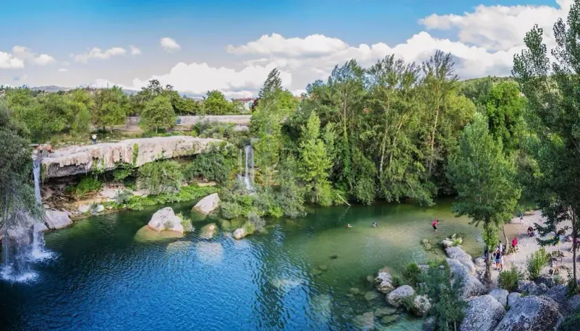 La cascada del peñón, con aguas cristalinas y rodeada de exuberante vegetación, invita a refrescarse. Personas disfrutan del baño y la naturaleza.