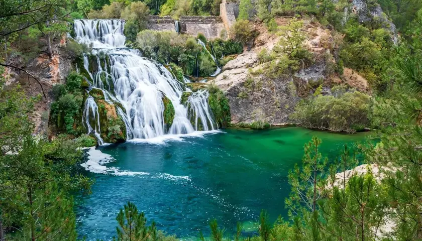 Cascada y laguna de Uña, con aguas turquesas y vegetación exuberante.