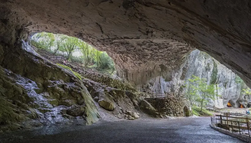 Interior de una cueva con escaleras de madera y piedra que llevan al exterior. Para saber zugarramurdi como llegar, sigue el camino.