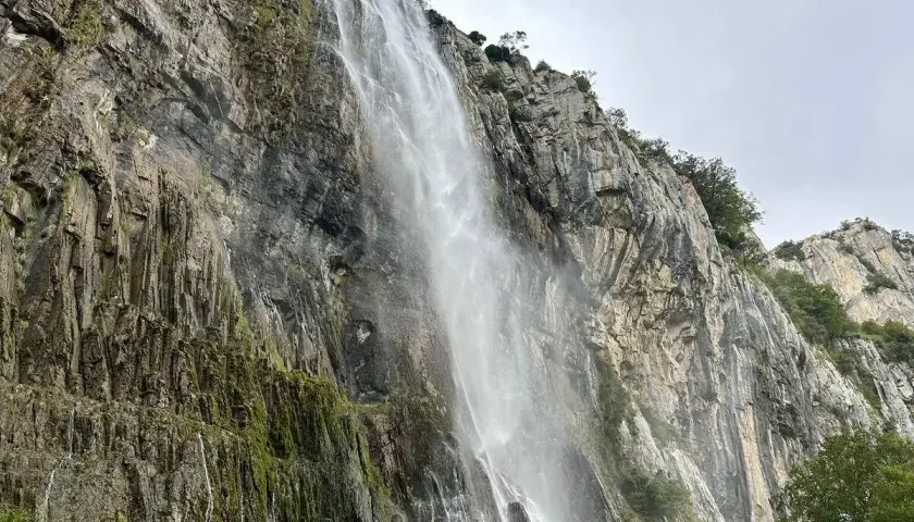 Majestuosa cascada del Ason cayendo por un imponente acantilado rocoso cubierto de vegetación.