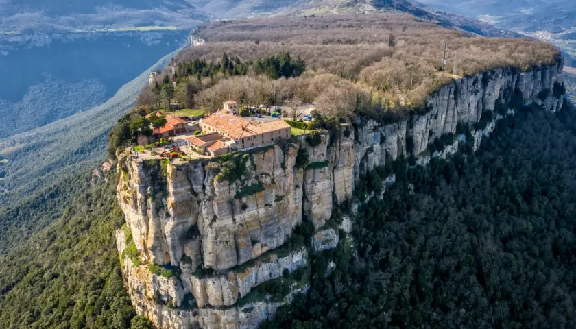 El santuari del Far se alza majestuoso sobre un acantilado, rodeado de montañas y bosques.