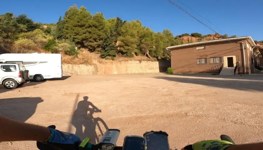 Encuentra la bogarra en este camino de tierra, con una caravana y un edificio de ladrillo al fondo.