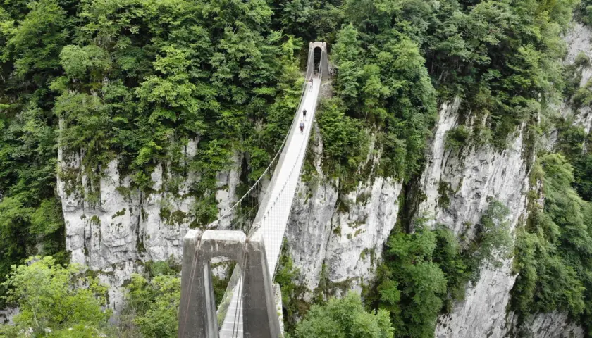 La pasarela de Holtzarte cruza un profundo cañón verde, con personas caminando sobre ella.