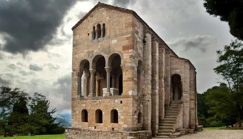 La iglesia Santa María del Naranco, joya prerrománica asturiana, se alza majestuosa bajo un cielo nublado.