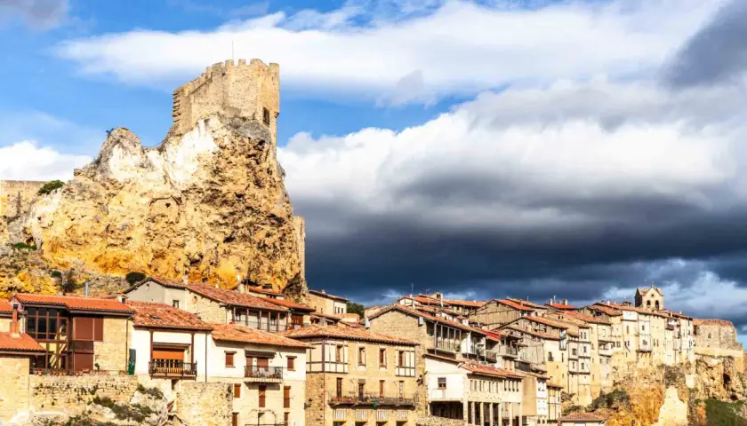 Pueblo medieval en un risco rocoso, con un castillo en la cima. Las casas se aferran a la ladera. Frias como llegar, un destino histórico.
