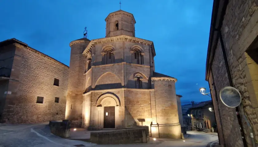 Las torres del río iluminadas al anochecer, con una iglesia románica y calles empedradas.