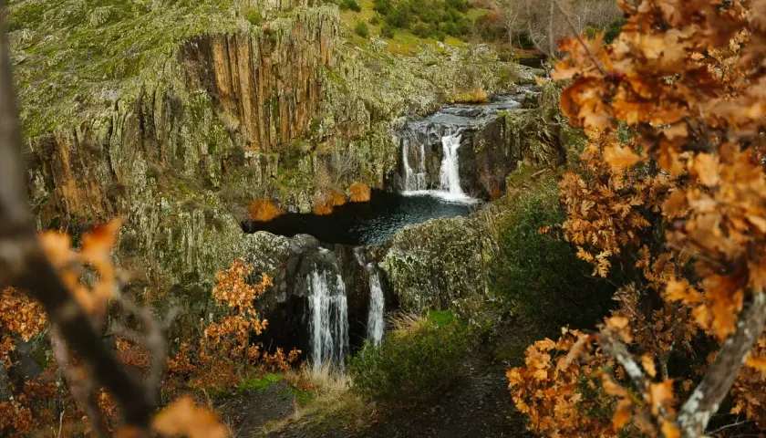 Cascada del Aljibe en otoño, con hojas doradas y rocas cubiertas de musgo.