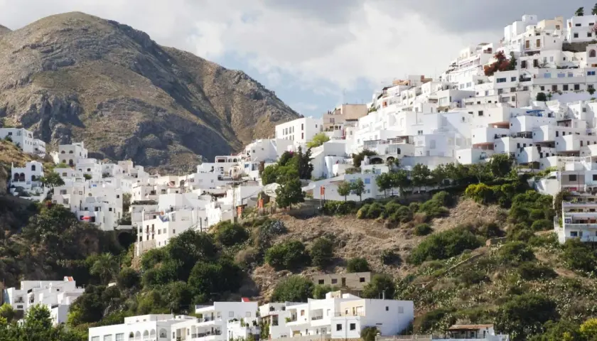 Casas blancas se aferran a una ladera montañosa, un laberinto de calles que invitan a descubrir Mojácar. ¿Cómo llegar? Sigue el sol.