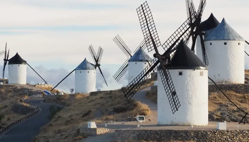 Los icónicos molinos de Consuegra se alzan sobre una colina, sus aspas recortadas contra un cielo nublado.