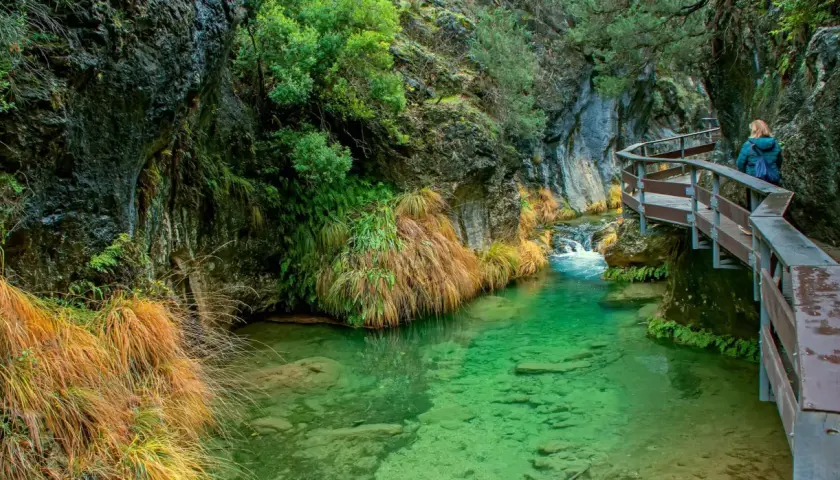 Un sendero de madera serpentea junto a un río de aguas cristalinas en la cerrada de Elías.
