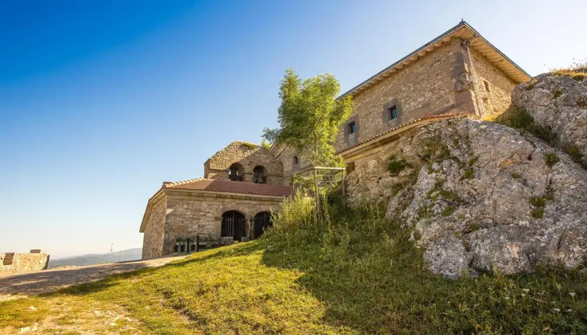 Antiguo santuario de oro en la cima de una colina rocosa, con un cielo azul brillante.