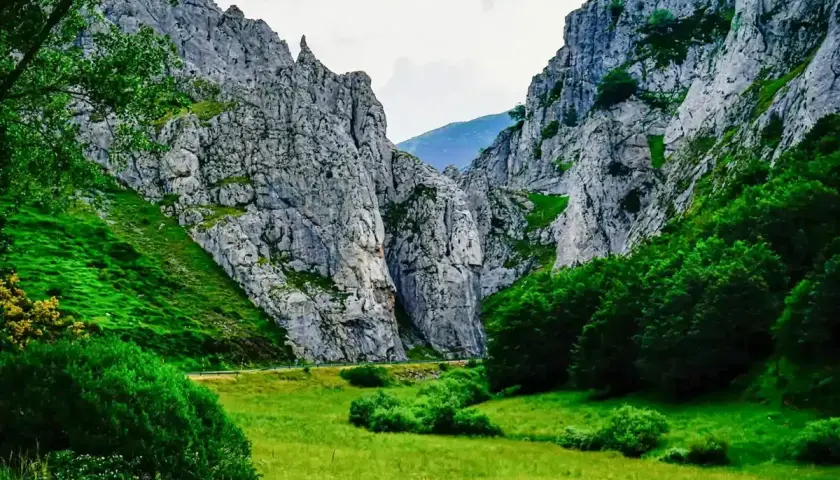 Majestuosas rocas flanquean un valle verde, donde la **cascada de Mazobre** se esconde entre la vegetación exuberante.