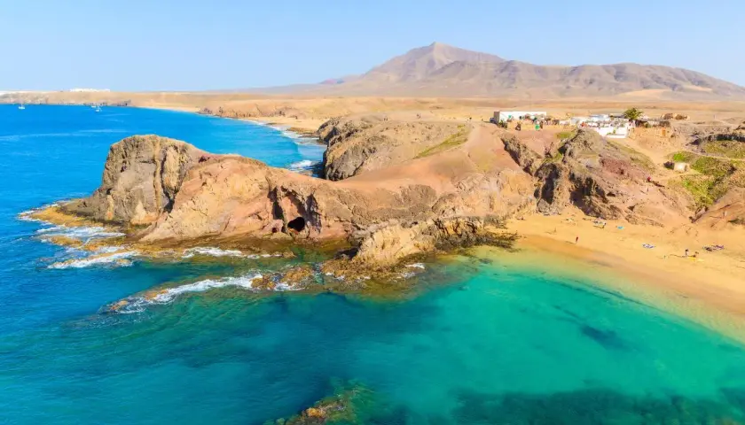 Aguas turquesas y arena dorada en una de las mejores playas de Lanzarote. Un paisaje volcánico se funde con el océano Atlántico.