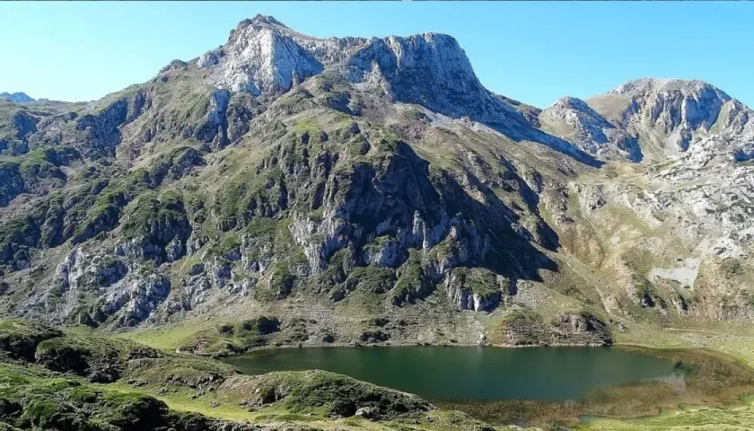 Majestuoso lago en la ruta Lagos de Saliencia, rodeado de imponentes montañas rocosas y vegetación verde.