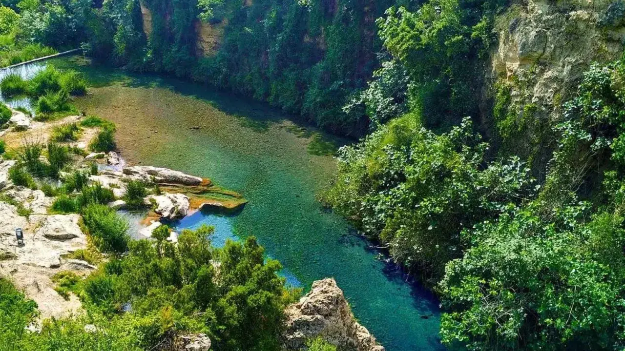 Un río de aguas cristalinas serpentea entre acantilados cubiertos de vegetación exuberante. Los lagos de Anna, un paraíso natural de tonos turquesa y verdes intensos.