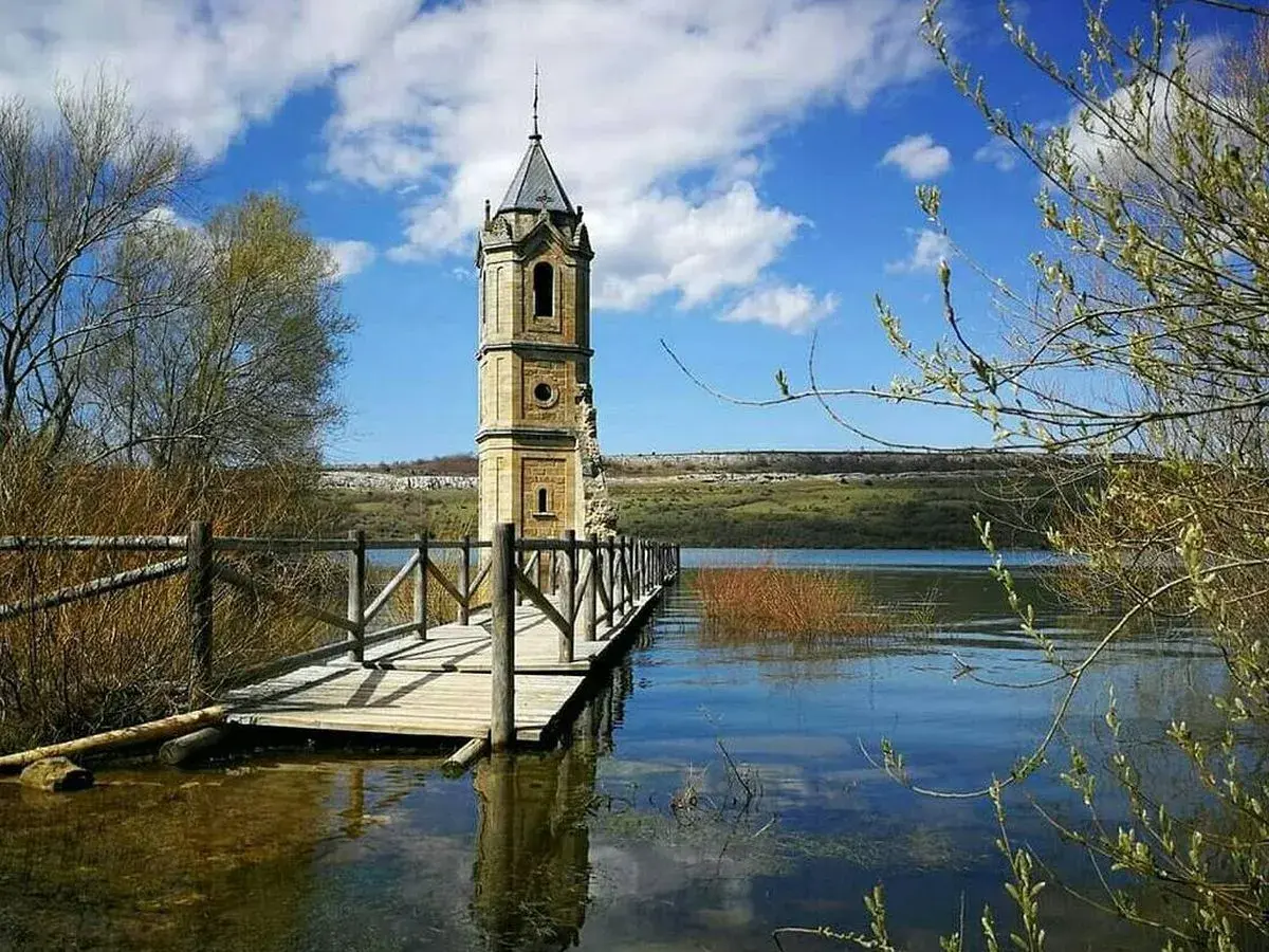 La **catedral de los peces**, una torre solitaria emerge del agua, conectada por un puente de madera.