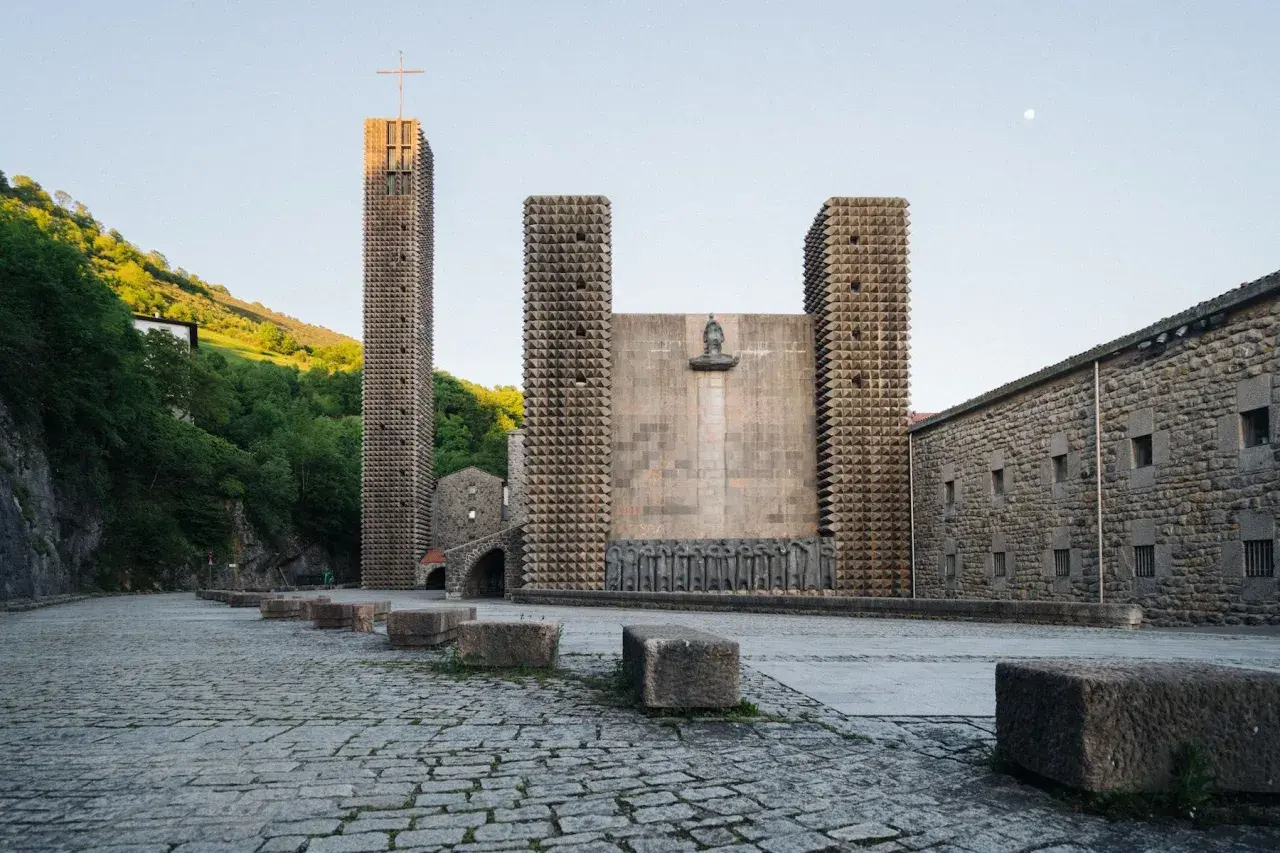 Santuario de Arantzazu con su torre alta, fachada de piedra y esculturas.