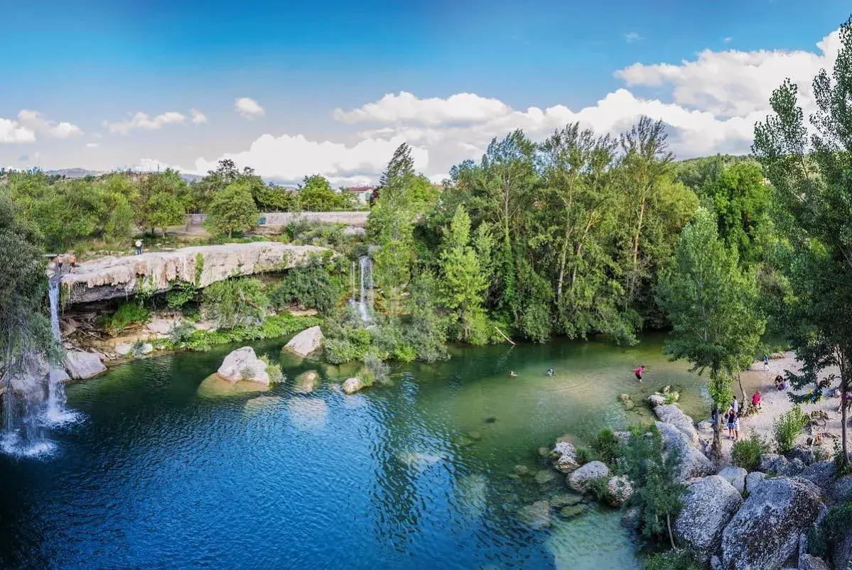 La cascada del peñón, con aguas cristalinas y rodeada de exuberante vegetación, invita a refrescarse. Personas disfrutan del baño y la naturaleza.