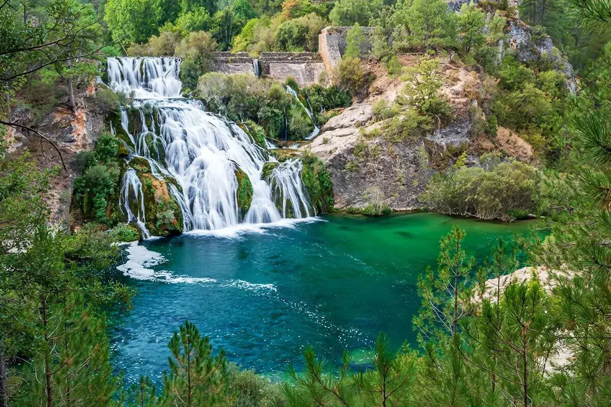 Cascada y laguna de Uña, con aguas turquesas y vegetación exuberante.