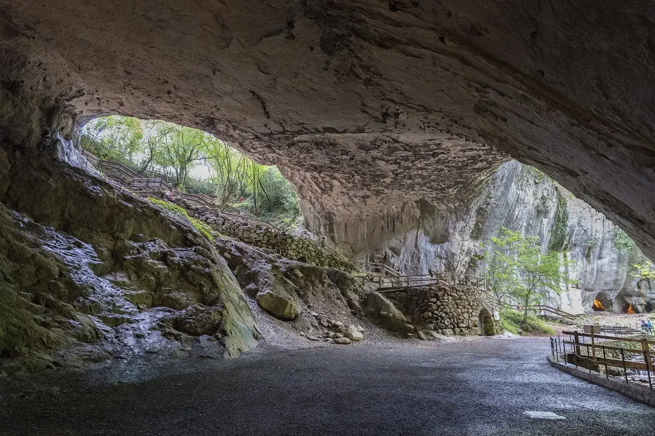 Interior de una cueva con escaleras de madera y piedra que llevan al exterior. Para saber zugarramurdi como llegar, sigue el camino.