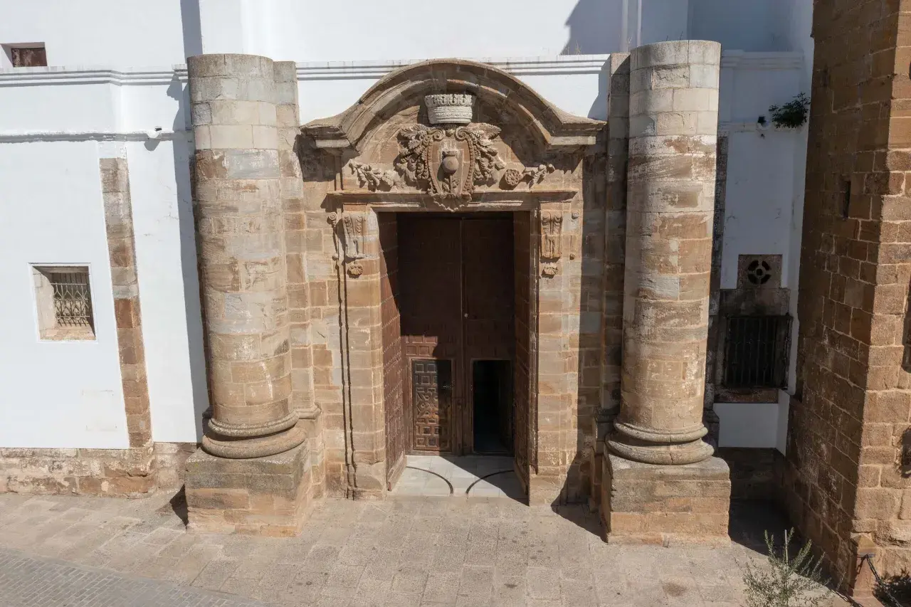 Impresionante portal de piedra con detalles ornamentales, flanqueado por columnas. Parece la entrada a una capilla Sixtina extremeña, invitando a descubrir su interior.