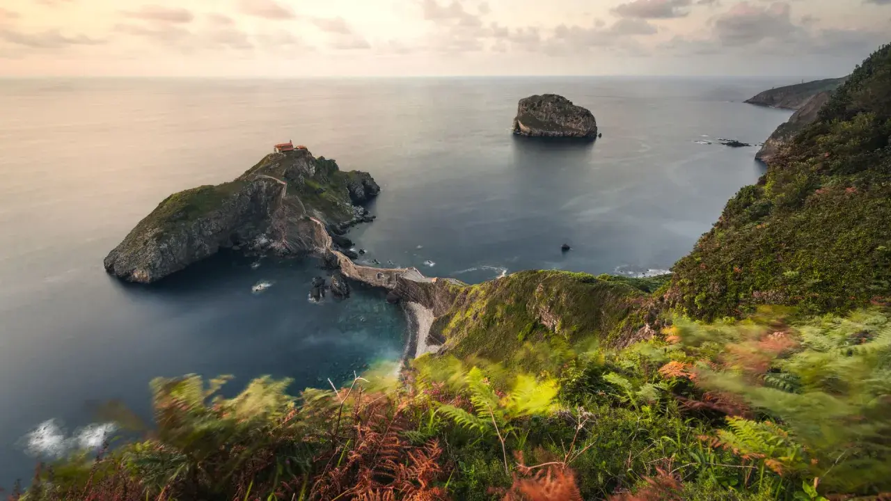 Las escaleras de San Juan de Gaztelugatxe serpentean hacia una ermita en una isla rocosa, rodeada por el mar Cantábrico.