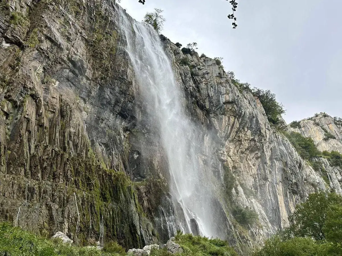 Majestuosa cascada del Ason cayendo por un imponente acantilado rocoso cubierto de vegetación.