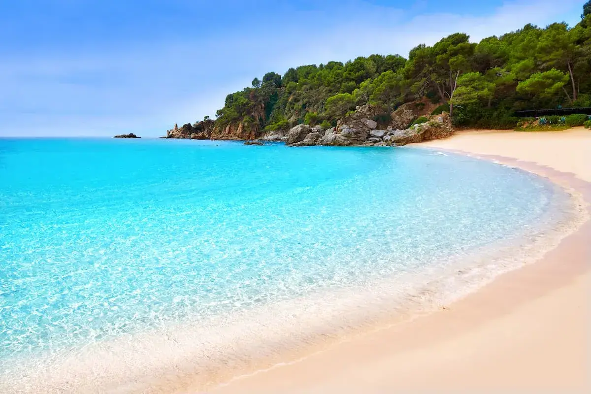 Aguas cristalinas y arena dorada en una cala idílica, un paraíso entre las playas cerca de Barcelona.