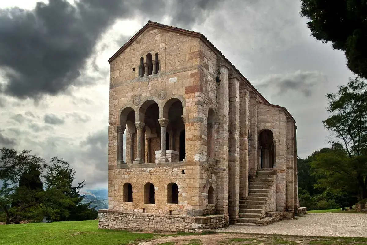 La iglesia Santa María del Naranco, joya prerrománica asturiana, se alza majestuosa bajo un cielo nublado.