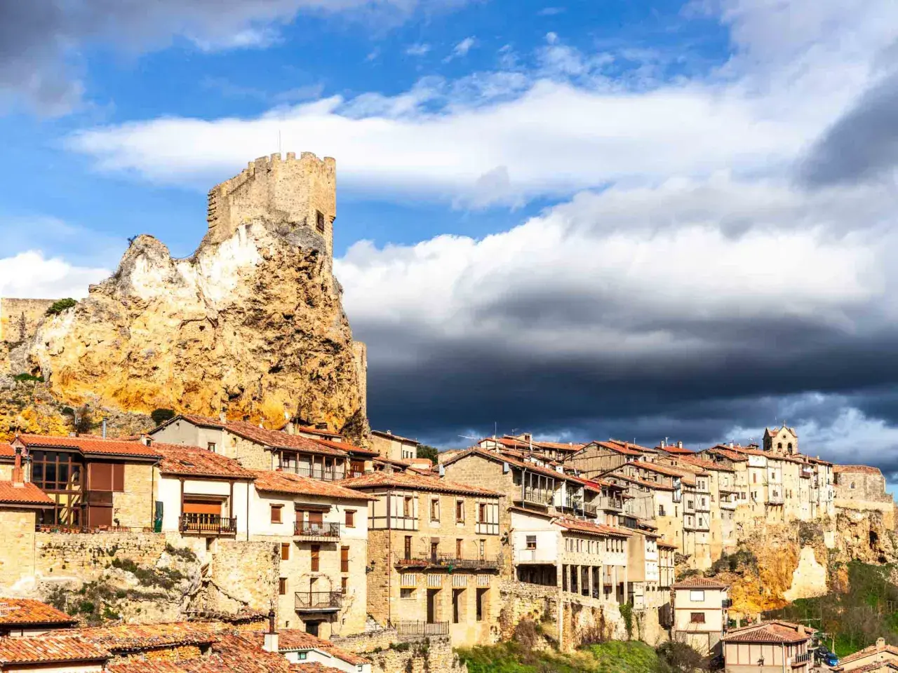 Pueblo medieval en un risco rocoso, con un castillo en la cima. Las casas se aferran a la ladera. Frias como llegar, un destino histórico.