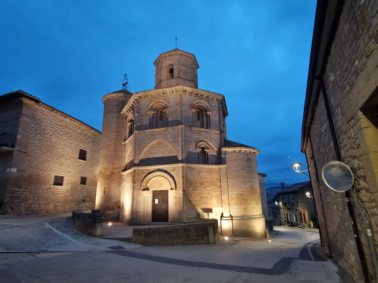 Las torres del río iluminadas al anochecer, con una iglesia románica y calles empedradas.
