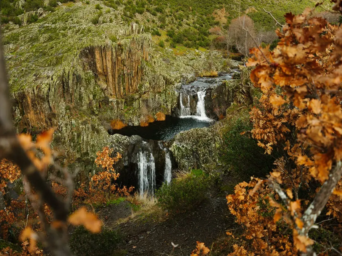 Cascada del Aljibe en otoño, con hojas doradas y rocas cubiertas de musgo.