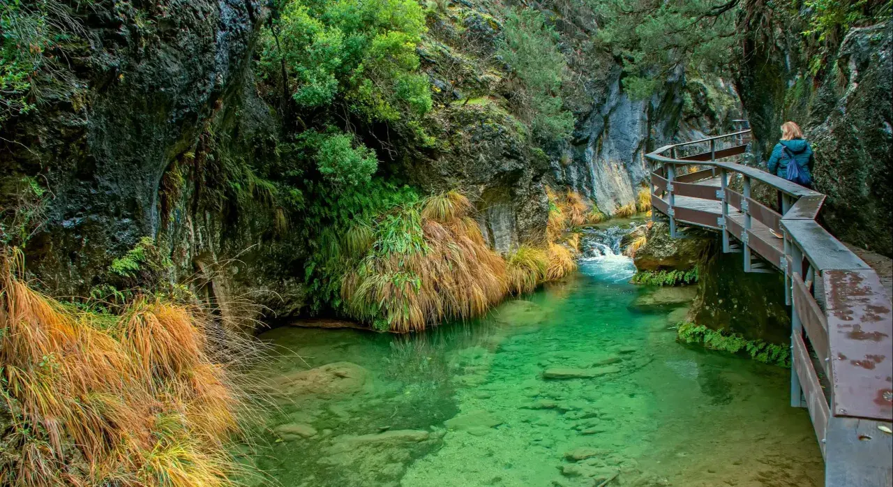 Un sendero de madera serpentea junto a un río de aguas cristalinas en la cerrada de Elías.