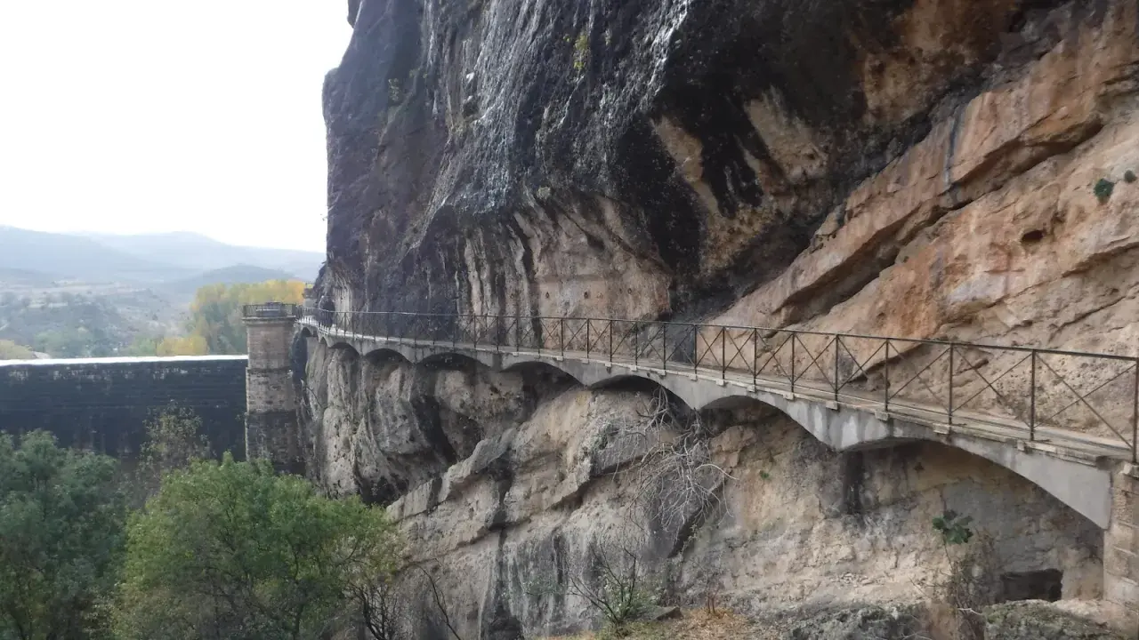 Un pontón de la oliva se aferra a un acantilado rocoso, con un camino bordeado de barandillas que serpentea a lo largo.