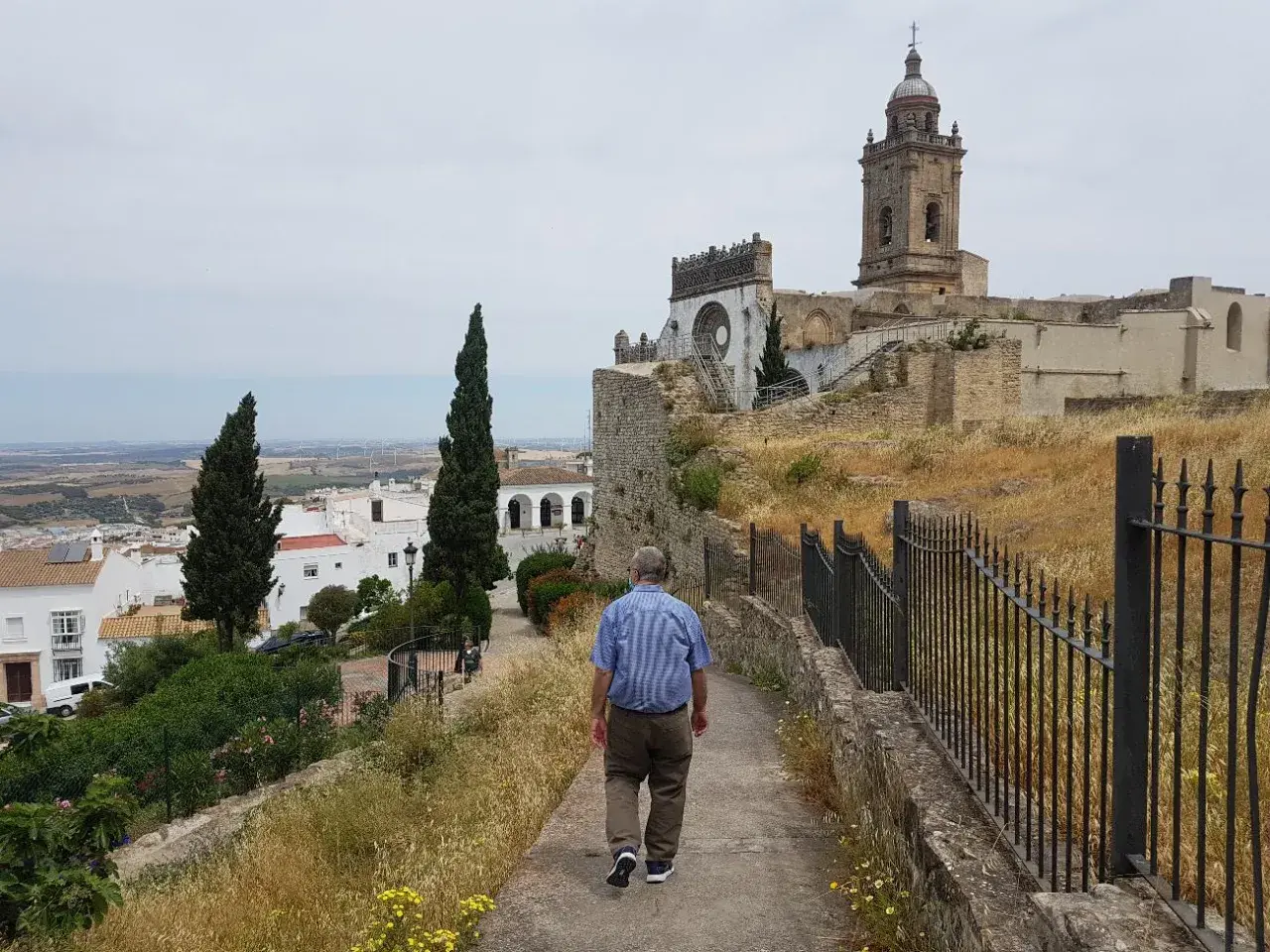 Hombre camina por sendero hacia iglesia en Medina Sidonia. Descubre cómo llegar a este pueblo blanco andaluz.