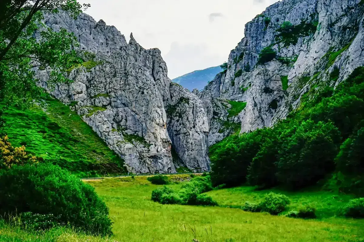 Majestuosas rocas flanquean un valle verde, donde la **cascada de Mazobre** se esconde entre la vegetación exuberante.