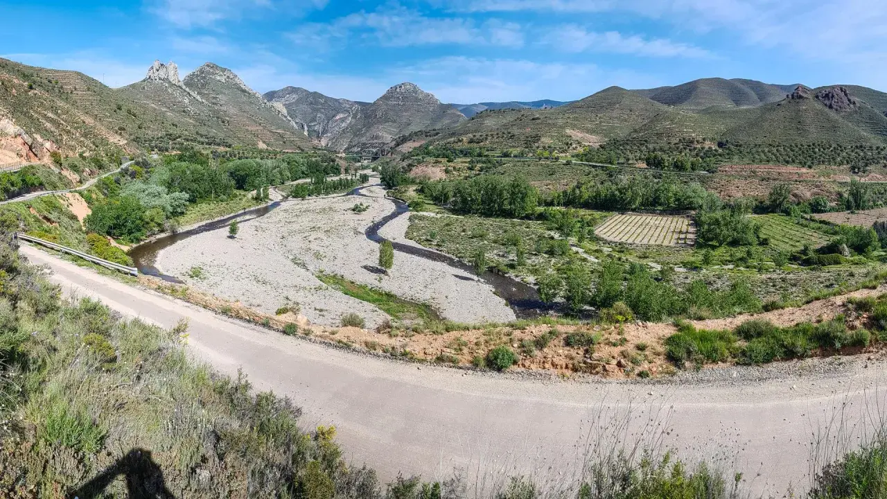 Paisaje montañoso con río y viñedos. La carretera serpentea, guiando hacia Arnedo.
