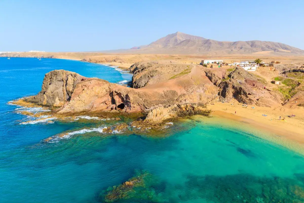 Aguas turquesas y arena dorada en una de las mejores playas de Lanzarote. Un paisaje volcánico se funde con el océano Atlántico.