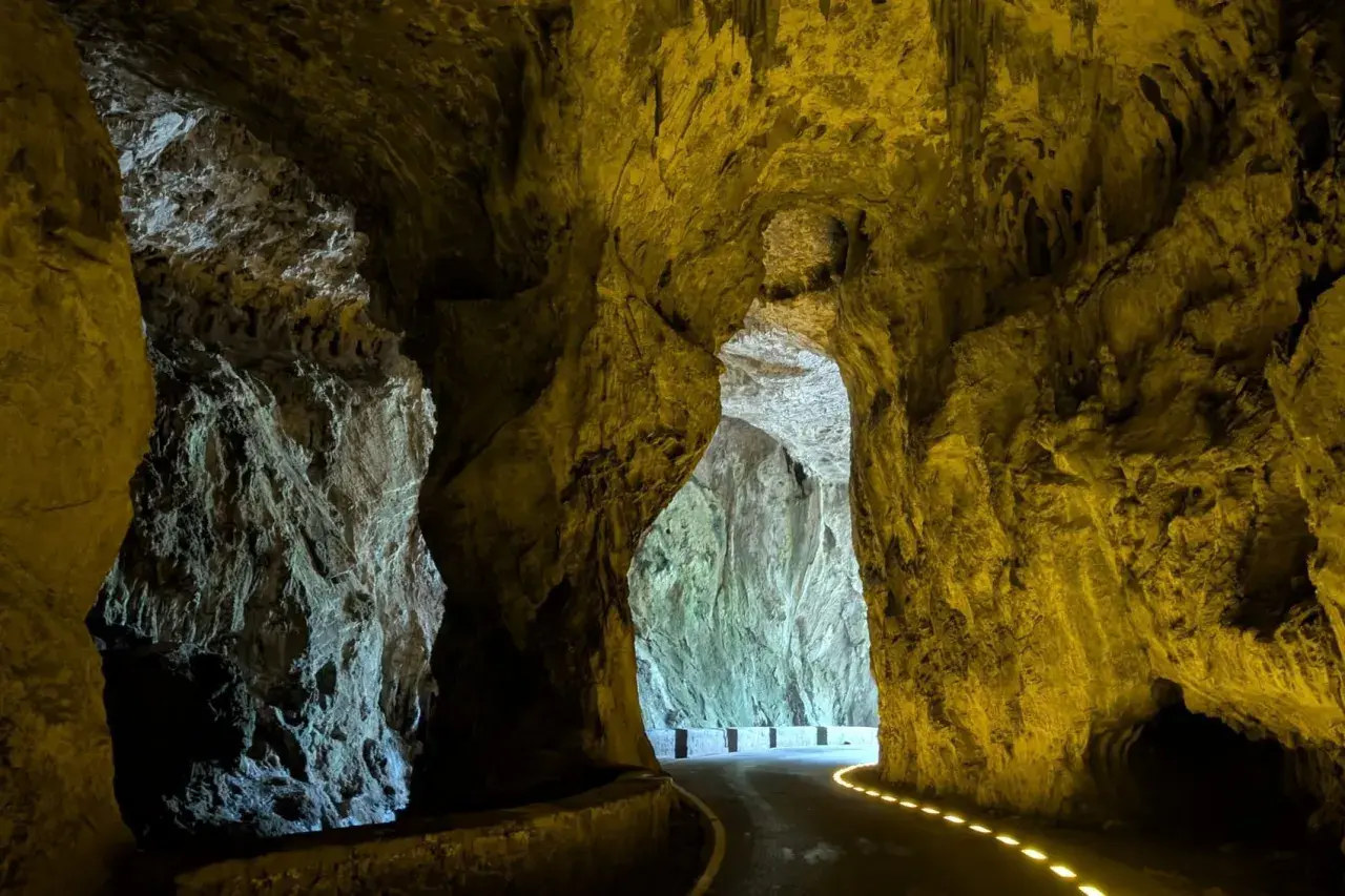 Un camino serpentea a través de las impresionantes cuevas del agua, iluminado por luces doradas que resaltan las formaciones rocosas.